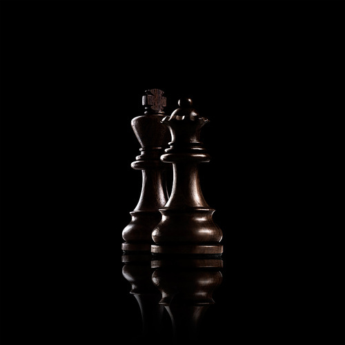 Chess game concept of black wooden king and queen, the most powerful figures standing together against dark background.