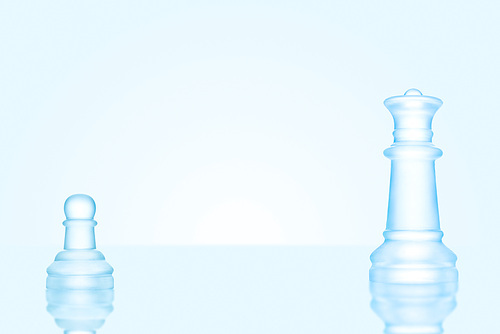 Leadership and bravery concept; an icy frosted single pawn staying against a queen on chessboard.