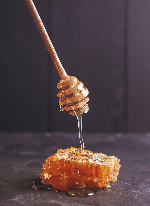 Honey drip and comb over black slate background