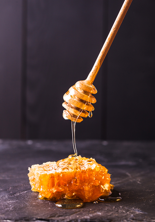 Honey drip and comb over black slate background