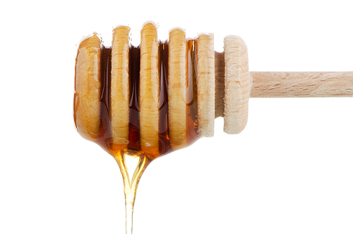Honey on wooden drizzler isolated on white