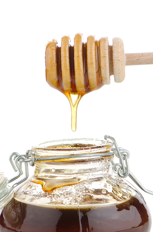 Jar of honey with wooden drizzler isolated on white