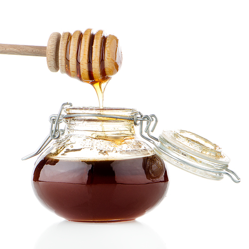 Jar of honey with wooden drizzler isolated on white
