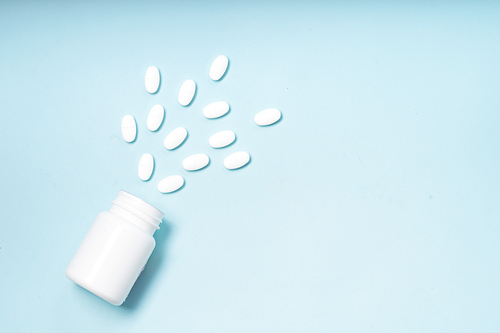 Pile of falling medical pills and bottle on blue background