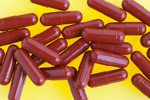 Macro view of red capsules on white yellow background.