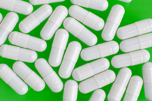 Macro view of white pills on white green background.