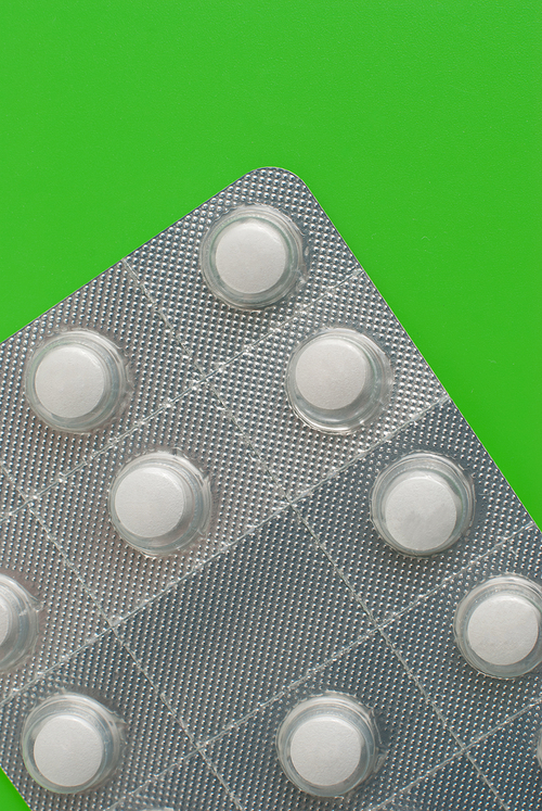 Macro view of white pills on green background.