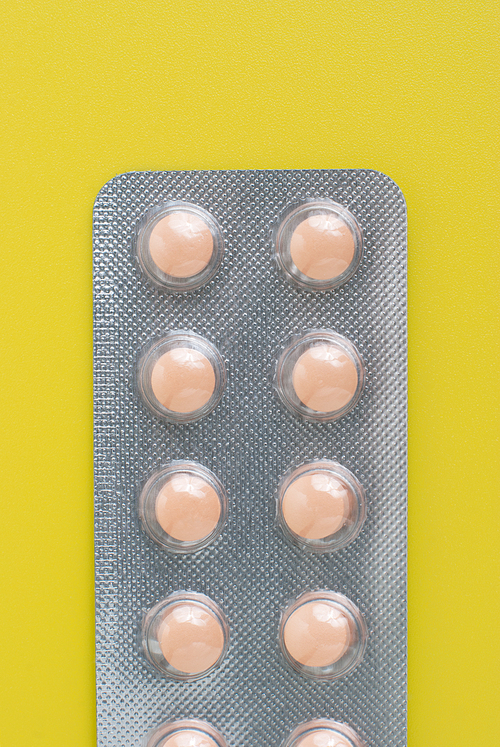 Macro view of medical pills on yellow background.