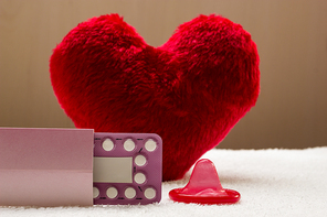 Medicine contraception love and birth control. Oral contraceptive pills condom on red heart shaped little pillow