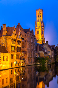 Historic medieval buildings along a canal in Bruges, Belgium at dusk.