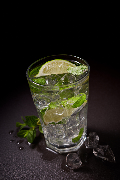 Homemade alcoholic mojito with lime and green mint on stone table