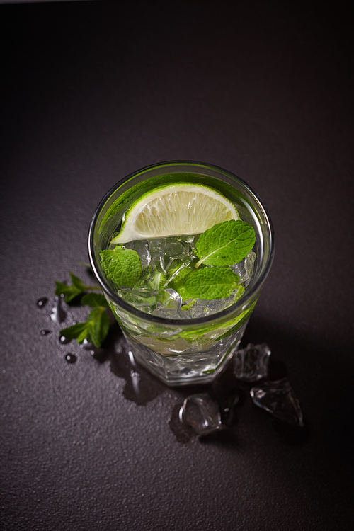 Cold refreshing summer lemonade mojito in a glass on a black background. Flat lay