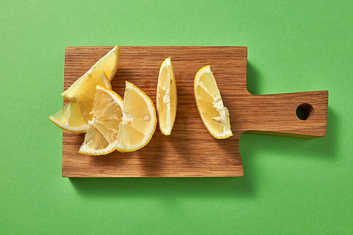 Healthy food concept. Top view of citrus fruit - slices of of yellow organic lemon on a wooden board on green.