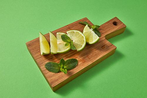 healthy food  concept. slices of juicy ripe organic green lime, green mint on a wooden cutting board on a green background. copy space.