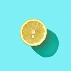 Fresh half organic lemon on blue background with reflection of shadows and space for text. Ingredient for mojito. Top view