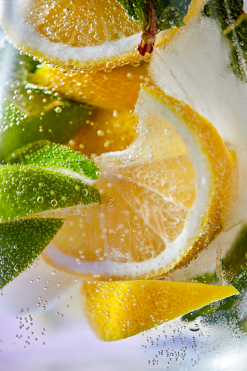 Macro photo of fresh lime and lemon slices with bubbles in the glass. Summer cold drink