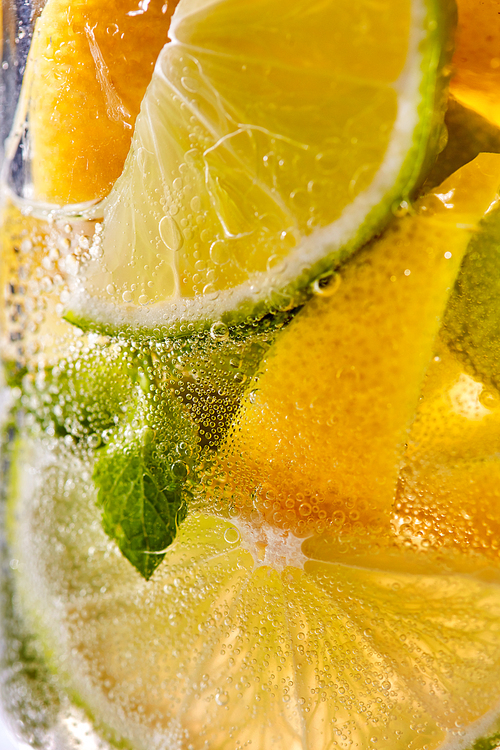 In a clear glass mint leaf, slices of lime and lemon with bubbles. Macro photo of summer cooling mojito