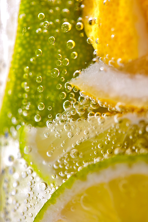 Homemade refreshing drink made from lemon and lime slices with bubbles. Macro photo of summer healthy lemonade