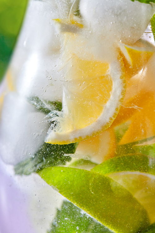 Cooling sparkling mojito cocktail in a glass with ice, mint and citrus slices. Cold alcoholic or nonalcoholic summer drinks.
