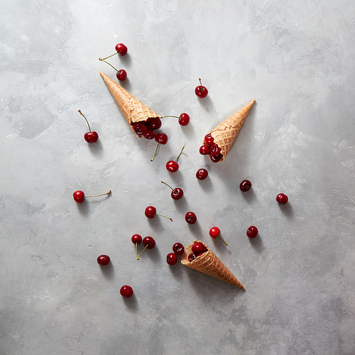 Freshly natural organic cherry fruits with wafer cones on a gray background , copy space. Top view. Summer concept of homemade cookies.
