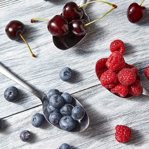 Mix of fresh organic berries - blueberries, cherries, raspberries on a gray wooden background. Top view.