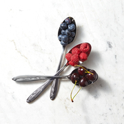 Freshly picked raspberry, cherry, blueberry in a spoons on a gray background with place under text. Spoons intersect on the table