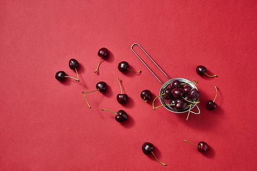Delicious sweet cherry on a colander on red background with place for text. Concept of vegetarian food.