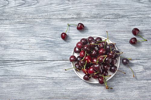 Natural organic berries - group of ripe juicy dark red cherry on a gray old wooden background. Flat lay.