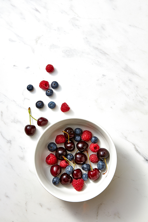 Organic berries ripe sweet natural in a ceramic dish on a gray stone background with place for text. Concept od detox diet eating.