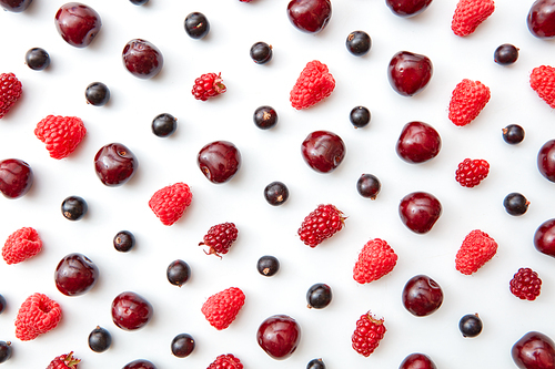 Pattern of juicy ripe raspberries, currants and cherries on a white background. Summer concept. Flat lay