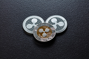 The back and front of the silver ripple coins on a black background. Conceptual image for worldwide cryptocurrency and digital payment system. Top view