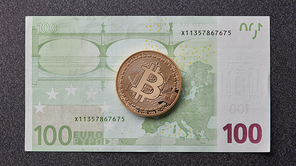 A symbolic coins of gold bitcoin on banknotes of one hundred euro exchange bitcoin cash for a euro on a dark background . Business, finance, technology concept of worldwide new cryptocurrency