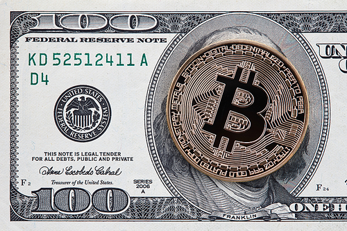 Physical version of gold Bitcoin on the one hundred american dollars. Business, finance, technology concept of worldwide new cryptocurrency