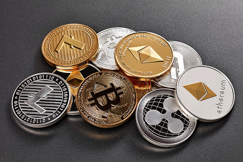 Gold and silver coins of various crypto-currencies on a dark background. Cryptocurrency and blockchain concept.
