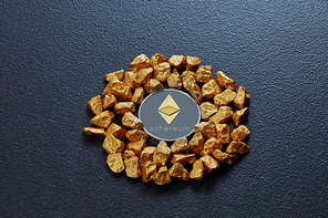 Gold nuggets in the form of a circle and a coin ethereum on a black concrete background. Concept of financing Bitcoin cryptocurrency in Noble metal
