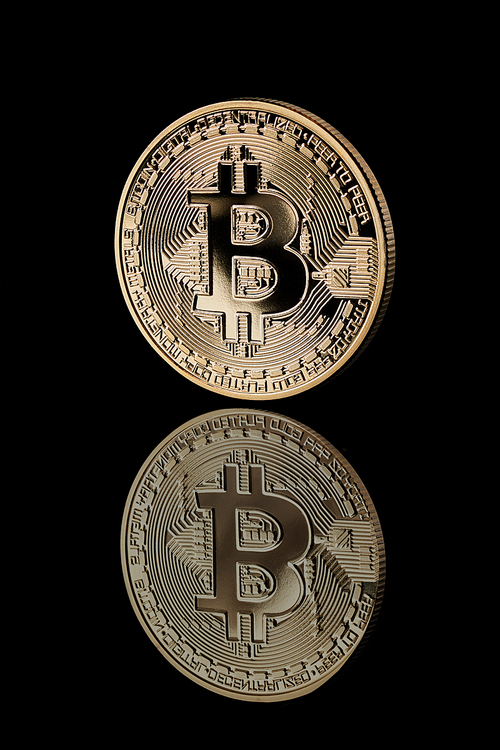 Gold Bitcoin Coin. Reflection of bitcoin icons on a black background. Bitcoin cryptocurrency. Business concept.