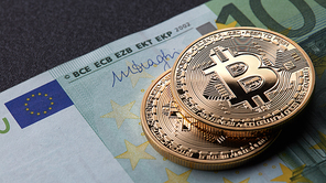 Two gold coins bitcoin stack on paper euro bill. Investing in crypto currency. Exchange bitcoin cash for a dollar.
