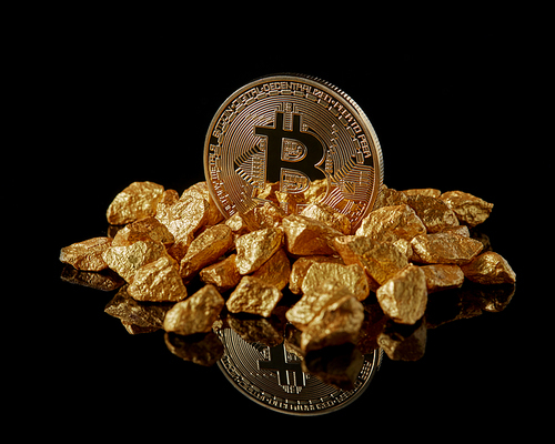 Golden bitcoin and gold lumps as world trends both isolated on black background with reflective surface. Digital virtual currency electronic money mining blockchain exchange innovation business