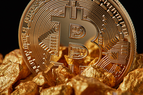 closeup of gold nugget and gold bitcoin coin on  background . bitcoin as desirable as digital gold concept. bitcoin cryptocurrency.