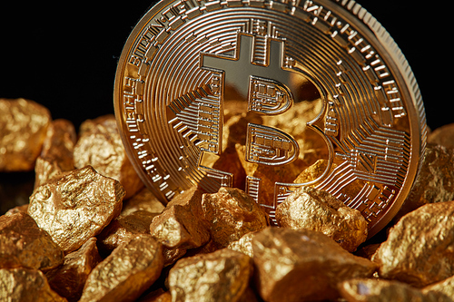 Closeup of Gold Bitcoin Coin and gold nugget on black background. Concept of financing Bitcoin cryptocurrency in Noble metal