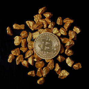 Bitcoin laying on stacked gold nuggets rendered on black background flat lay. Bitcoin as desirable as digital gold concept. Bitcoin cryptocurrency.