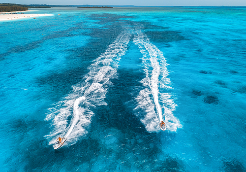 Aerial view of floating water scooter in blue water at sunny day in summer. Holiday in Indian ocean, Zanzibar, Africa. Top view of jet ski in motion. Tropical seascape with moving motorboat. Extreme