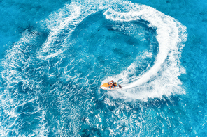 Aerial view of floating water scooter in blue water at sunny day in summer. Holiday in Indian ocean, Zanzibar, Africa. Top view of jet ski in motion. Tropical seascape with moving motorboat. Extreme
