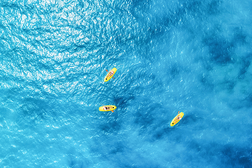 Aerial view of the people in kayaks in the blue sea at sunny bright day in summer. Zanzibar, Africa. Top view of canoe. Landscape with clear azure water, boats. Sport and leisure. Lifestyle