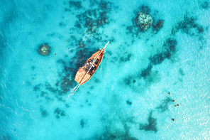 Aerial view of the fishing boats in clear blue water at sunset in summer. Top view from drone of boat, sandy beach. Indian ocean. Travel in Zanzibar, Africa. Landscape with sailboats, sea. Seascape