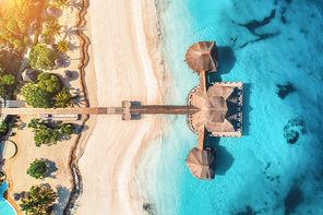 Aerial view of beautiful hotel in Indian ocean at sunrise in summer. Zanzibar, Africa. Top view.  Building on the sea. Aerial landscape with wooden hotel, clear azure water, sandy beach. Luxury resort