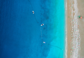 Aerial view of boats in mediterranean sea in Oludeniz,Turkey. Beautiful summer seascape with boats, clear azure water and sandy beach in sunny day. Top view of yachts from drone. Nature background