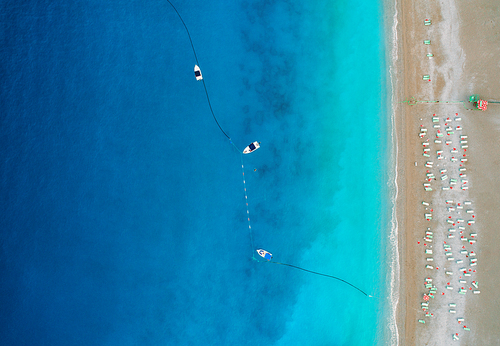 Aerial view of boats in mediterranean sea in Oludeniz,Turkey. Beautiful summer seascape with boats, clear azure water and sandy beach in sunny day. Top view of yachts from drone. Nature background