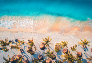 aerial view of umbrellas, palms on the sandy beach of blue sea at . summer travel in zanzibar, africa. tropical landscape with palm trees, parasols, people, sand, waves. top view from the air