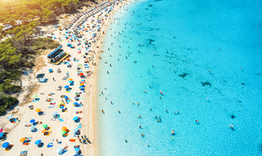 Aerial view of sandy beach with colorful umbrellas, swimming people in sea coast with transparent blue water, green trees at sunny day in summer. Travel in Mallorca, Balearic islands, Spain. Top view
